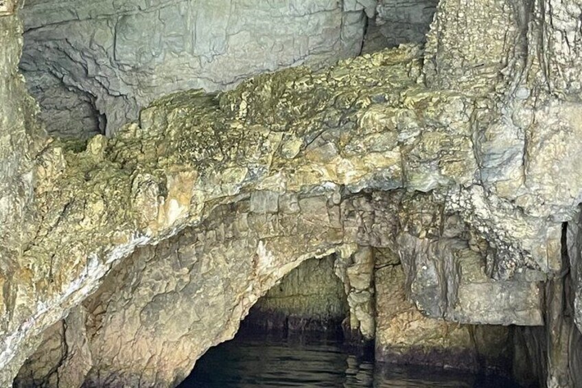 Una cueva con una formación rocosa en arco natural y una piscina en la base. 5
