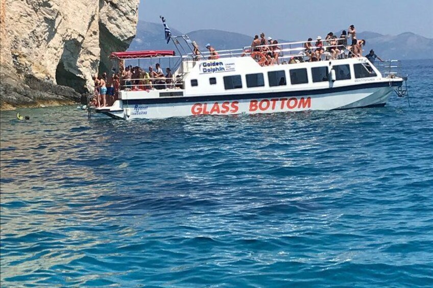 A boat named 'Glass Bottom' with people on board, near a rocky coastline. 3