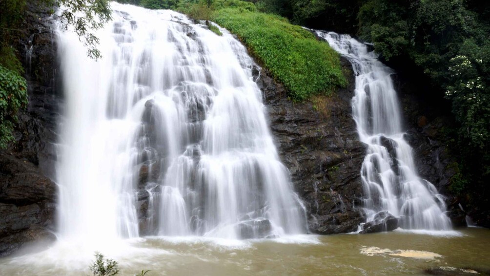 A multi-tiered waterfall cascading over rocks in a lush green forest. 2