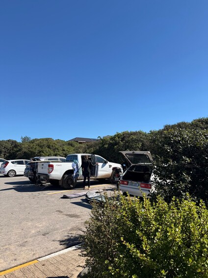 A white pickup truck with its hood open, parked in a lot with other vehicles. 5