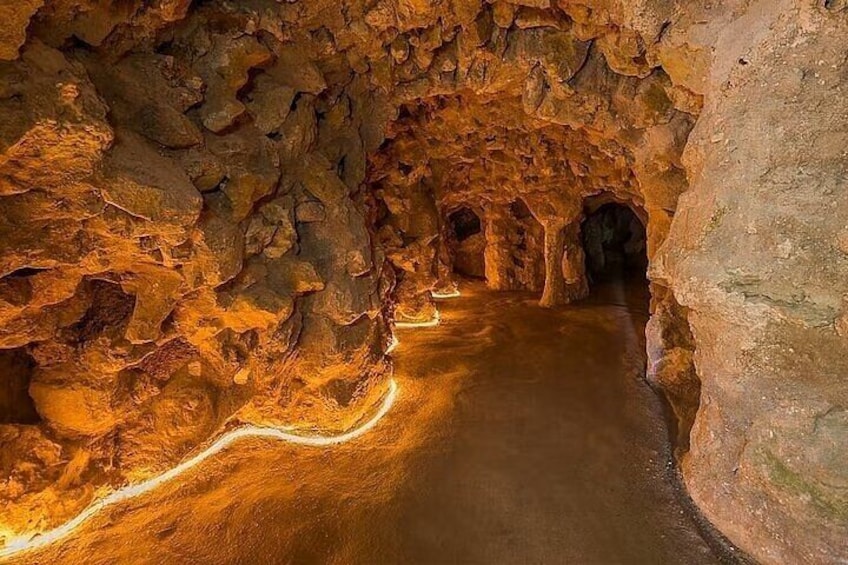 A cave with a winding path and illuminated by artificial lighting. 3
