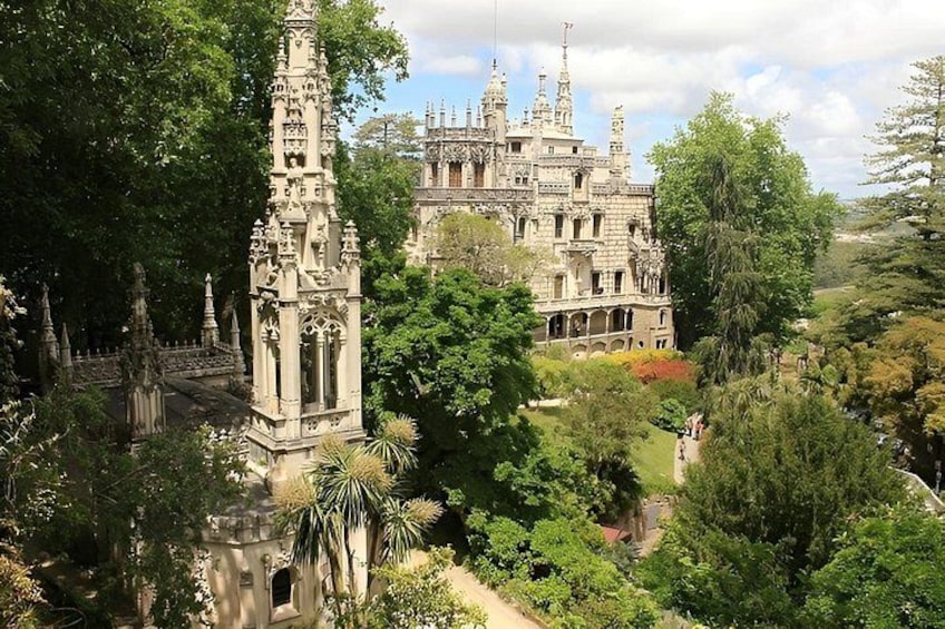 A Gothic-style castle surrounded by lush greenery and a tall, ornate tower. 5