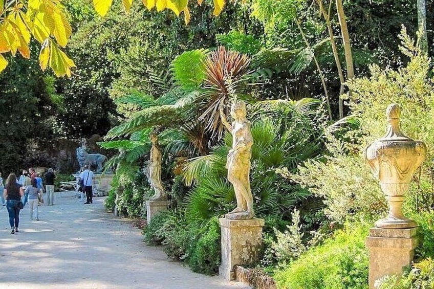 A pathway lined with statues and lush greenery. 4