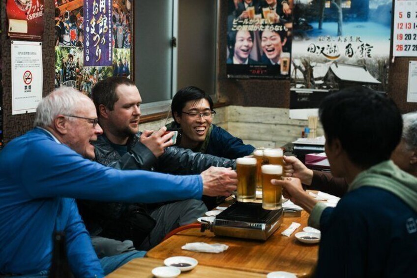 A group of people toasting with beer glasses at a table in a restaurant. 1
