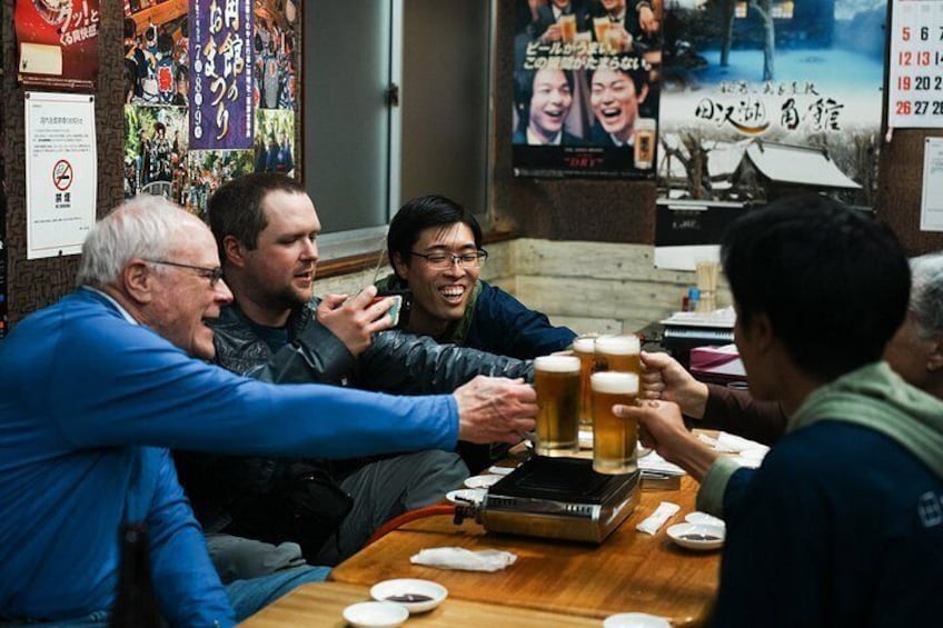 Un grupo de personas sentadas alrededor de una mesa brindando con vasos de cerveza. 1