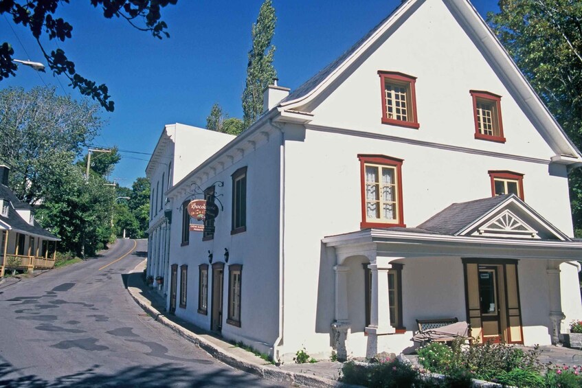 A white building with red trim, a porch, and a street leading up to it. 2