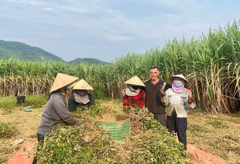 People harvesting sugarcane in a field with a mountainous backdrop. 2