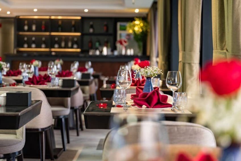 Interno di un ristorante con tavoli apparecchiati, tovaglioli rossi e bicchieri da vino. 3