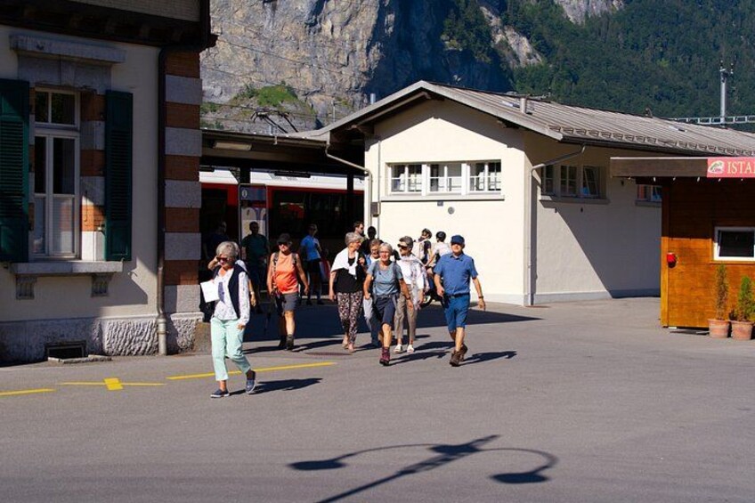 A group of people walking towards a building with a mountain backdrop. 4