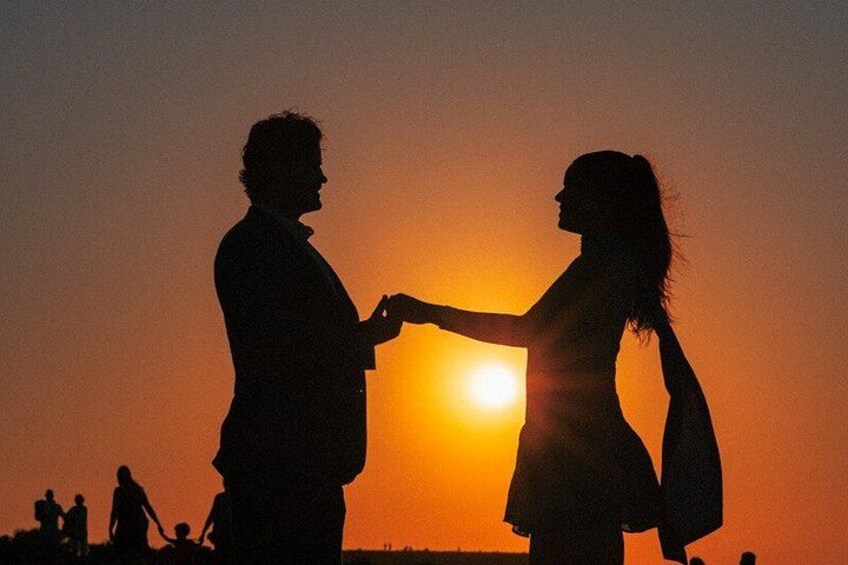 Silhouetten van een stel dat hand in hand loopt voor een zonsondergang. 5