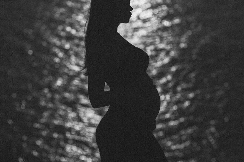 Silhouet van een zwangere vrouw, buiten, met bomen op de achtergrond. 2