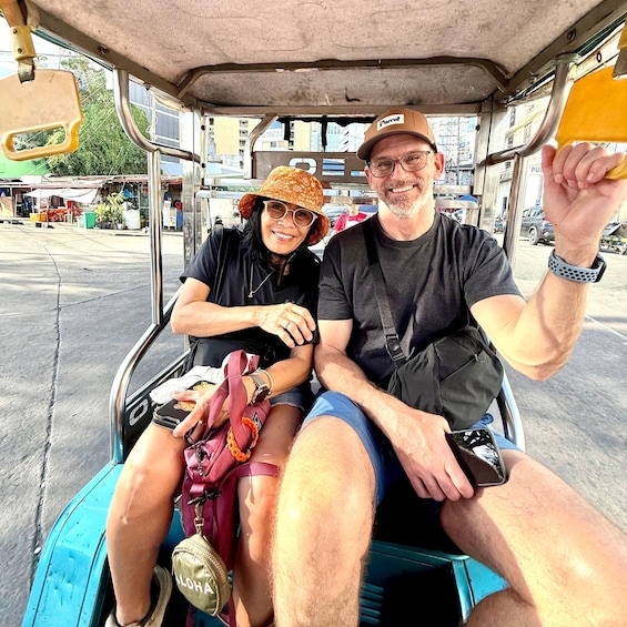 Two people seated in a tuk-tuk, with one holding a phone. 5