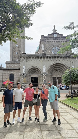 A group of people posing in front of a historic building with statues and star decorations. 4