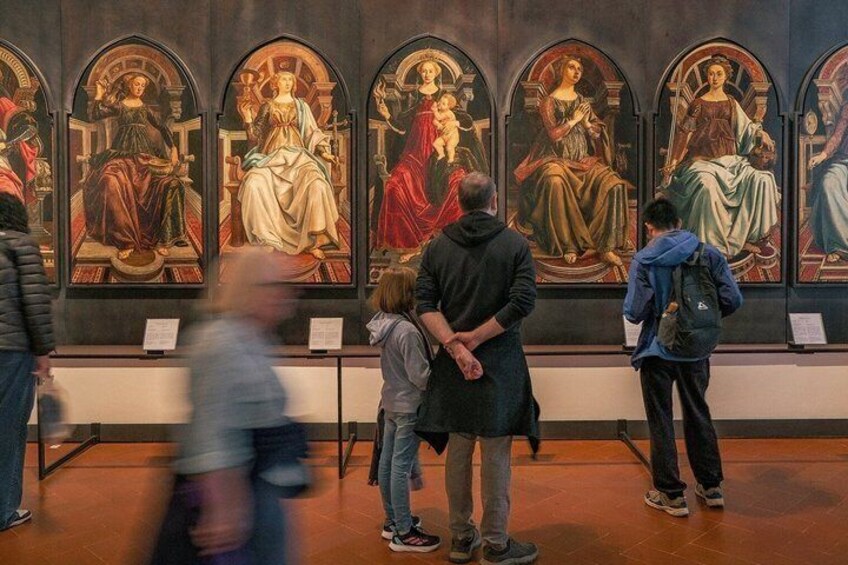Et museumsinteriør, hvor besøgende ser på en række religiøse malerier. 4