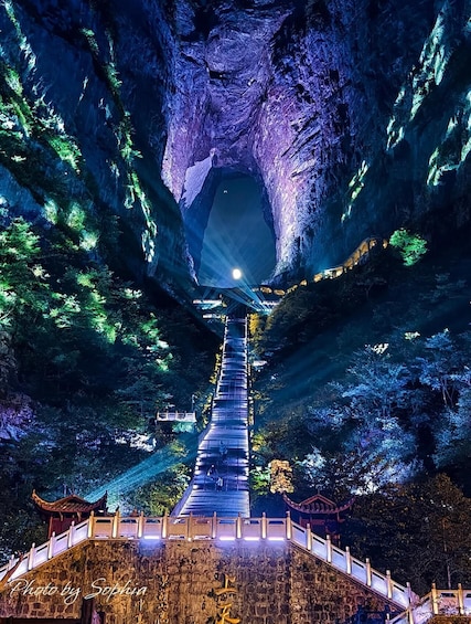 A stone bridge leading through a cave with a light at the end. 5