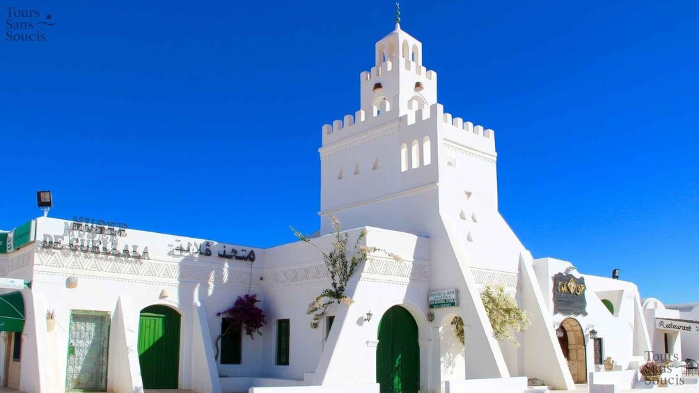 A white building with a tower and green doors. 3