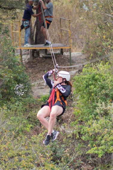 A person zip-lining through a forested area with a safety harness and helmet. 2
