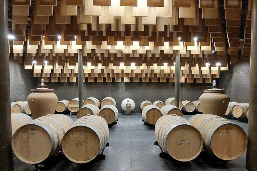 A wine cellar with wooden barrels and a unique geometric ceiling design. 2