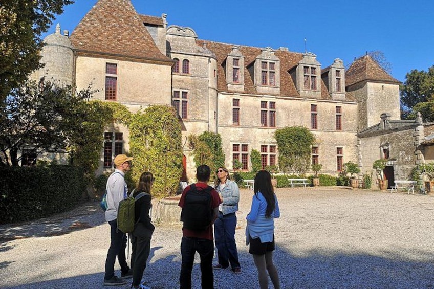 A historic building with a courtyard, surrounded by trees and gravel. 5