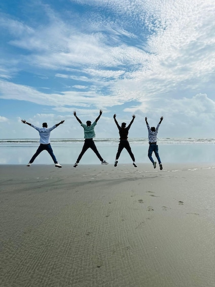 Four people jumping on a beach with a calm sea and a cloudy sky. 1