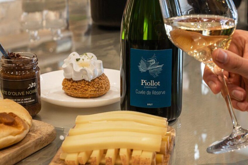 A bottle of Pioillot champagne, a dessert with whipped cream, and a jar of chocolate spread on a table. 1
