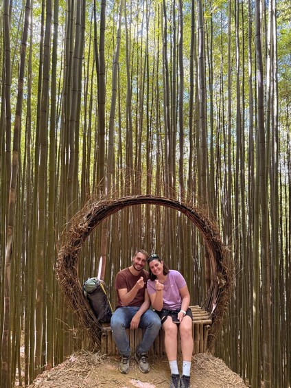 Two people sitting on a circular wooden bench in a bamboo forest. 4