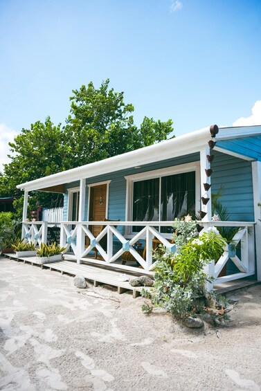 A coastal house with a white porch, blue siding, and a sandy driveway. 5