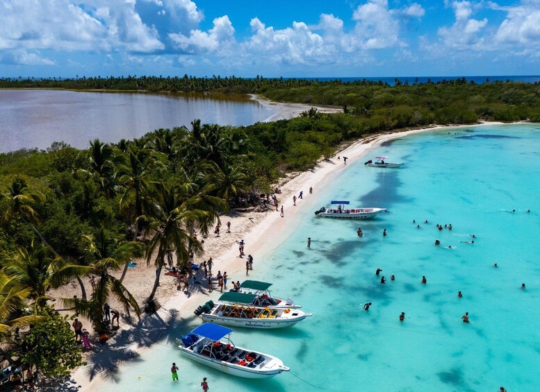 A tropical beach with clear turquoise waters, palm trees, and several boats anchored near the shore. 4