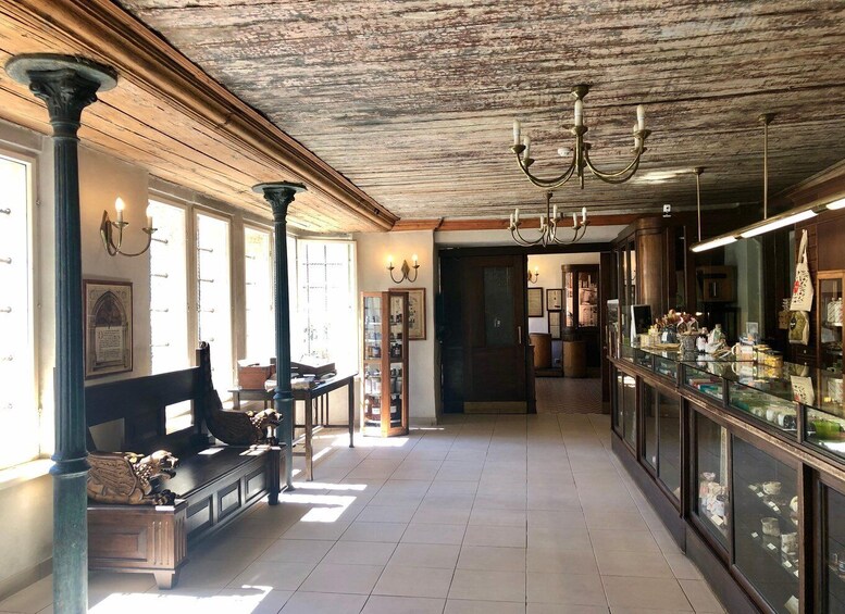 A vintage interior with wooden beams, a chandelier, and a display case with various items. 5