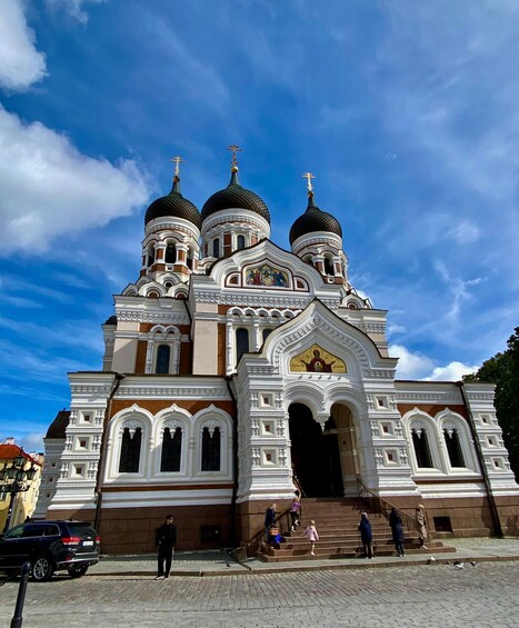 A large church with three domes and a golden cross on top. 1