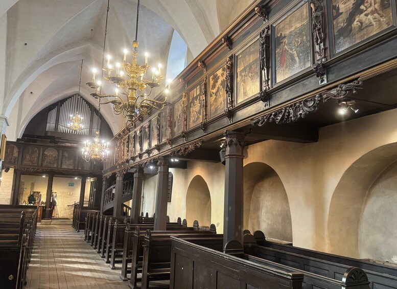 An interior of a church with wooden pews, a high ceiling, and a chandelier. 3