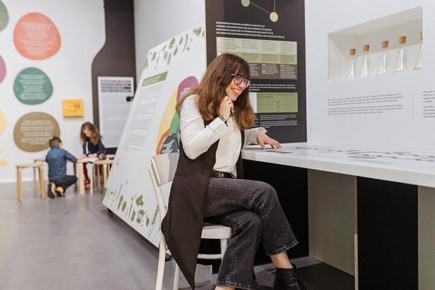 Una persona seduta a una scrivania con un poster e un monitor di computer in una stanza con esposizioni didattiche. 2