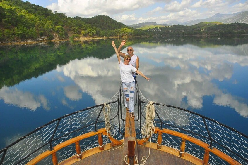 A boat with two people on a calm lake surrounded by greenery and mountains. 4