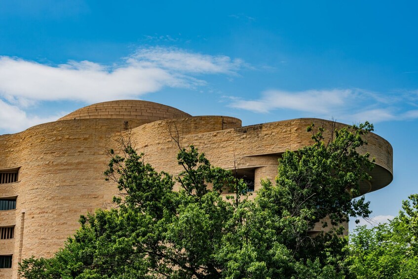 Un grande edificio circolare con un tetto curvo, circondato da alberi verdi e rigogliosi. 4