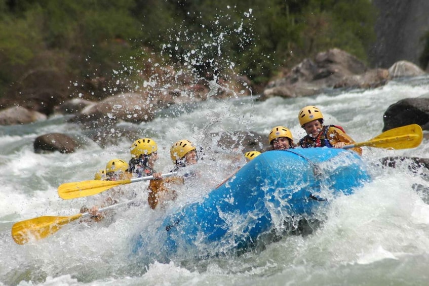 A group of people in a blue raft navigating a river with rapids. 5