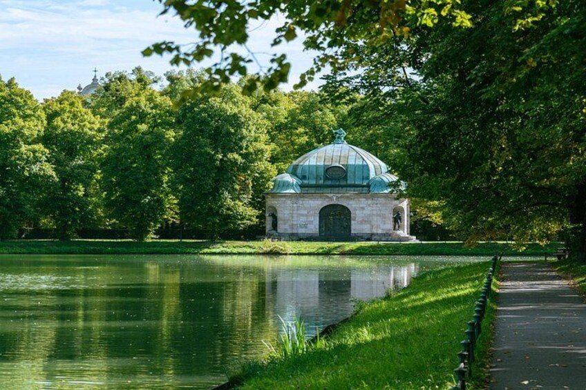 A serene park with a pond, a gazebo, and lush greenery. 1