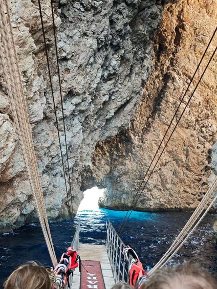 A rope bridge over a body of water with rocky cliffs on either side. 5