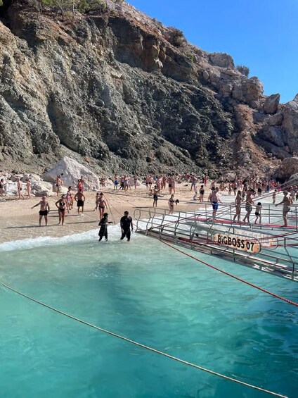 A crowded beach with people in swimwear, a rocky cliff in the background, and a lifeguard tower labeled 'BIGBOSS07'. 4
