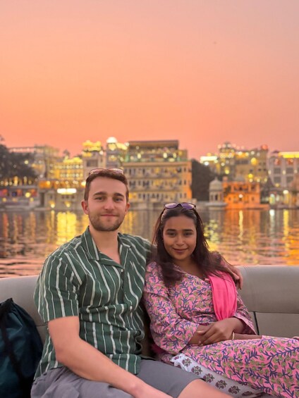 A couple sitting on a couch with a cityscape and water in the background. 5