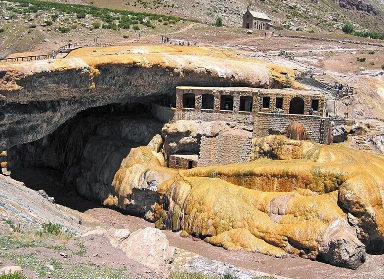 A large cave opening with a historic building complex nearby. 4
