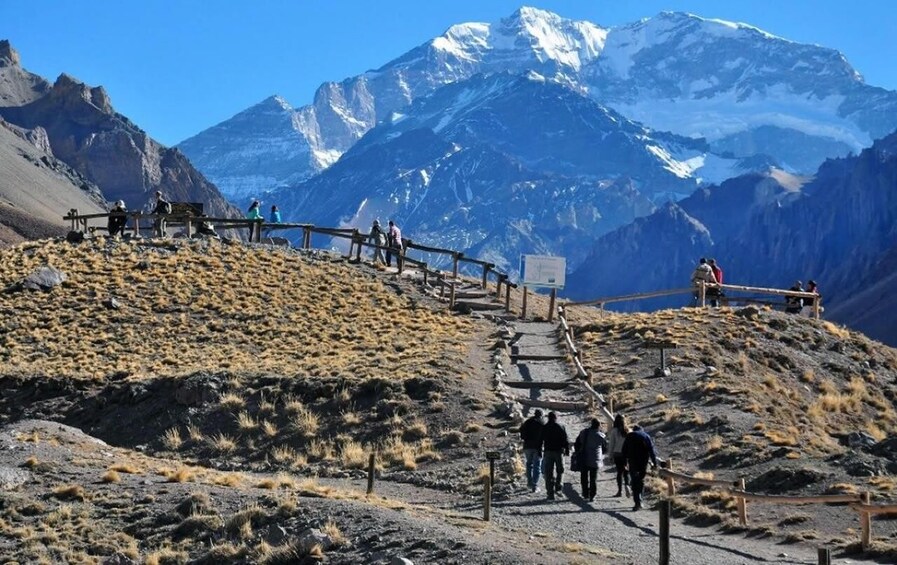 A mountainous hiking trail with wooden railings and a clear sky. 3