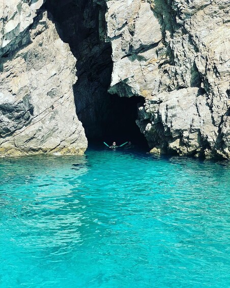 A person swimming in a natural pool with clear turquoise water, surrounded by rocky cliffs. 4