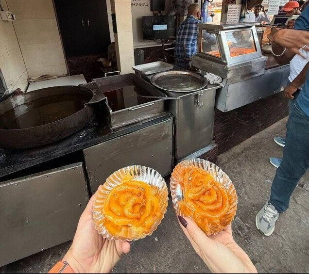 Two people holding paper cones with a spiral-shaped dessert. 2