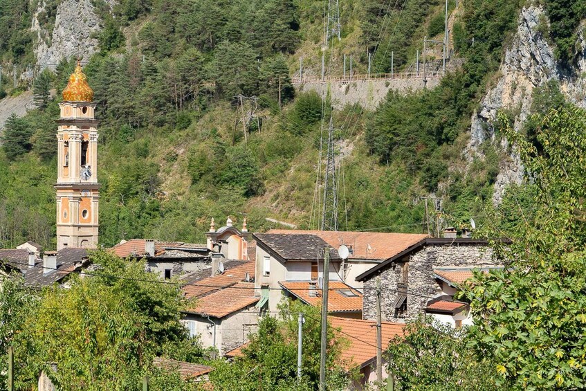 A village with a prominent church tower, surrounded by terraced houses and a mountainous backdrop. 5