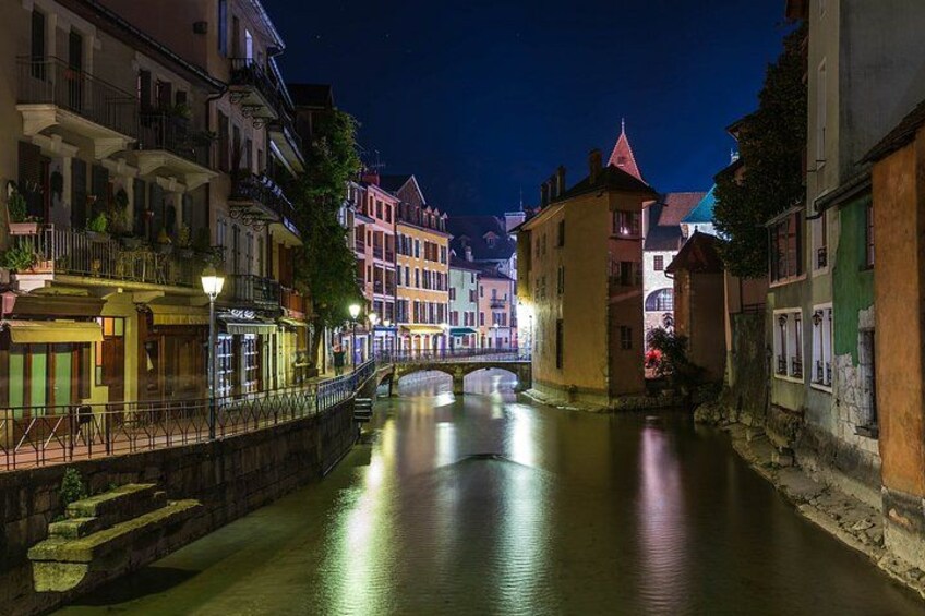 A nighttime river scene with illuminated buildings and a bridge. 2