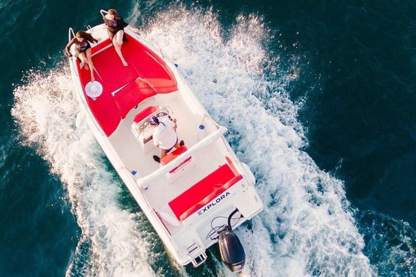 A red and white boat with two people on board, moving through the water. 4
