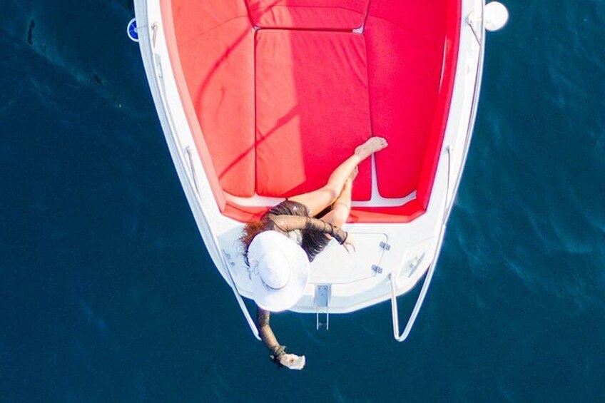 A person lying on a boat with a red canopy, surrounded by water. 3