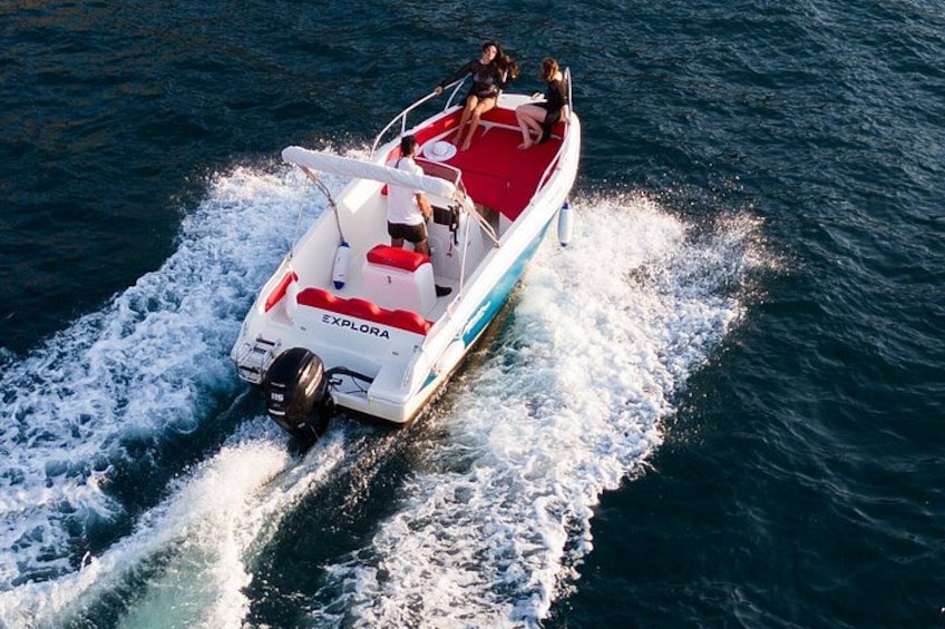 A white and red motorboat with the name 'EXPLORA' on the back, moving through the water. 1