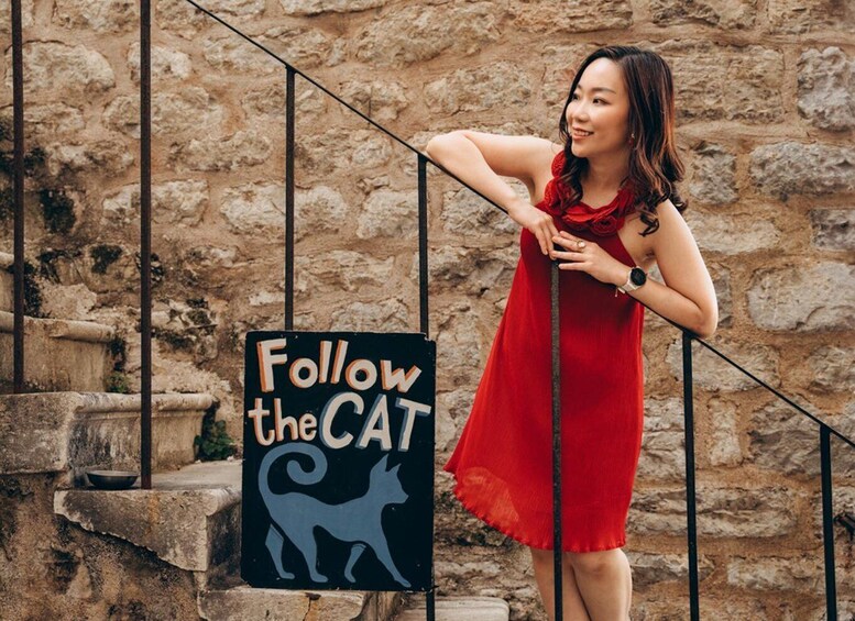 A person in a red dress standing next to a sign that says 'Follow the CAT' with a cat silhouette. 5