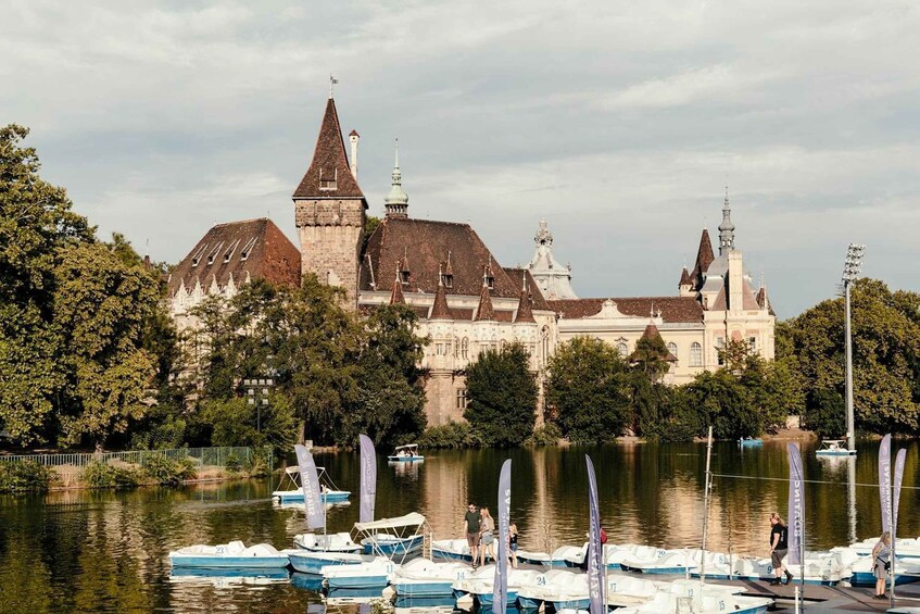 A historic building with multiple spires, a lake with boats, and a forested area. 4